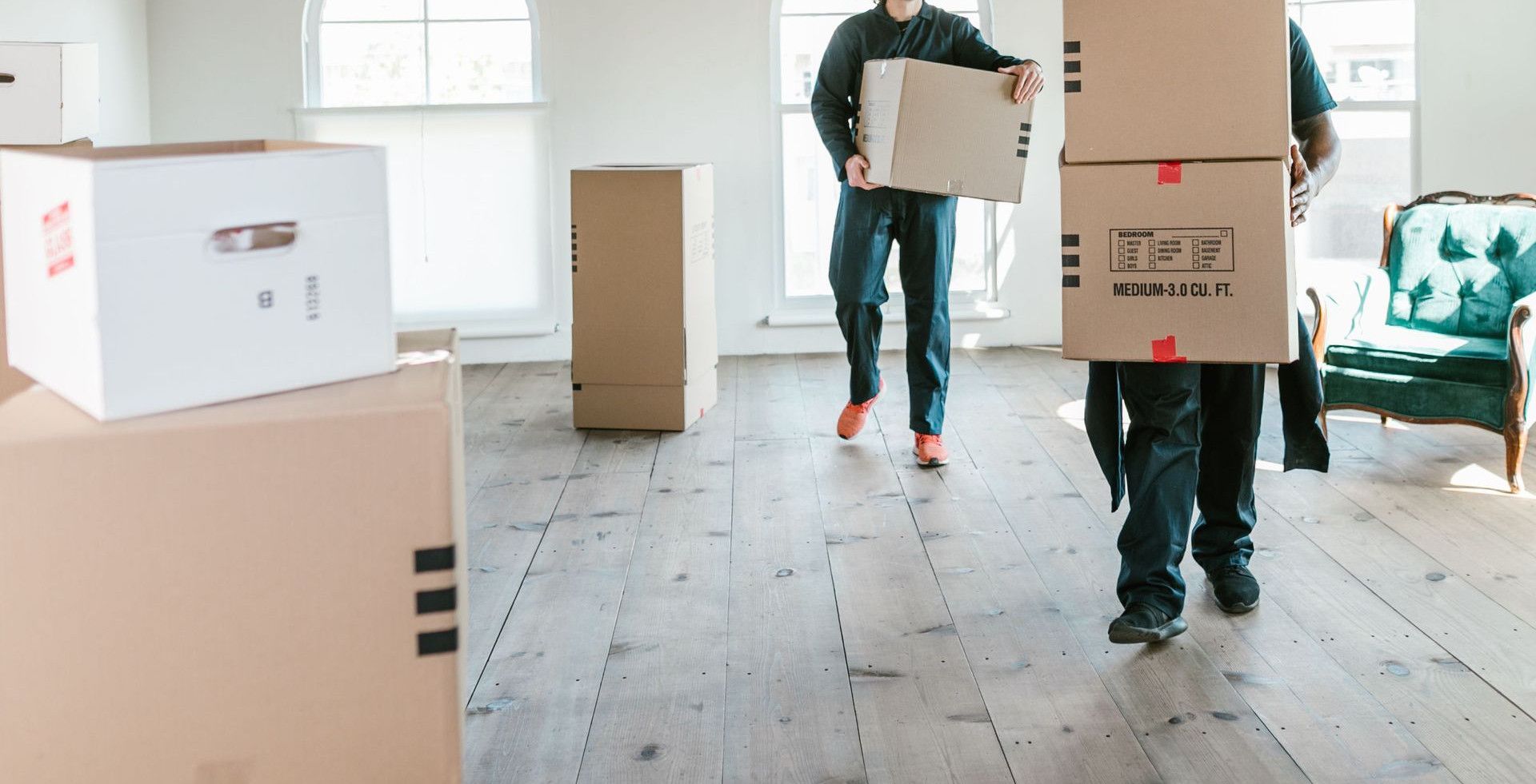 Two movers carrying boxes in a sunlit room, ready to assist with relocation.