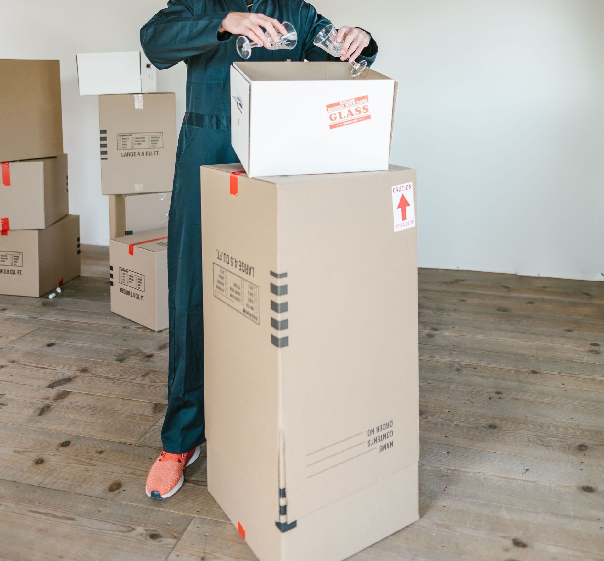 Man sealing moving boxes in a bright industrial setting. Ideal for relocation and logistics themes.