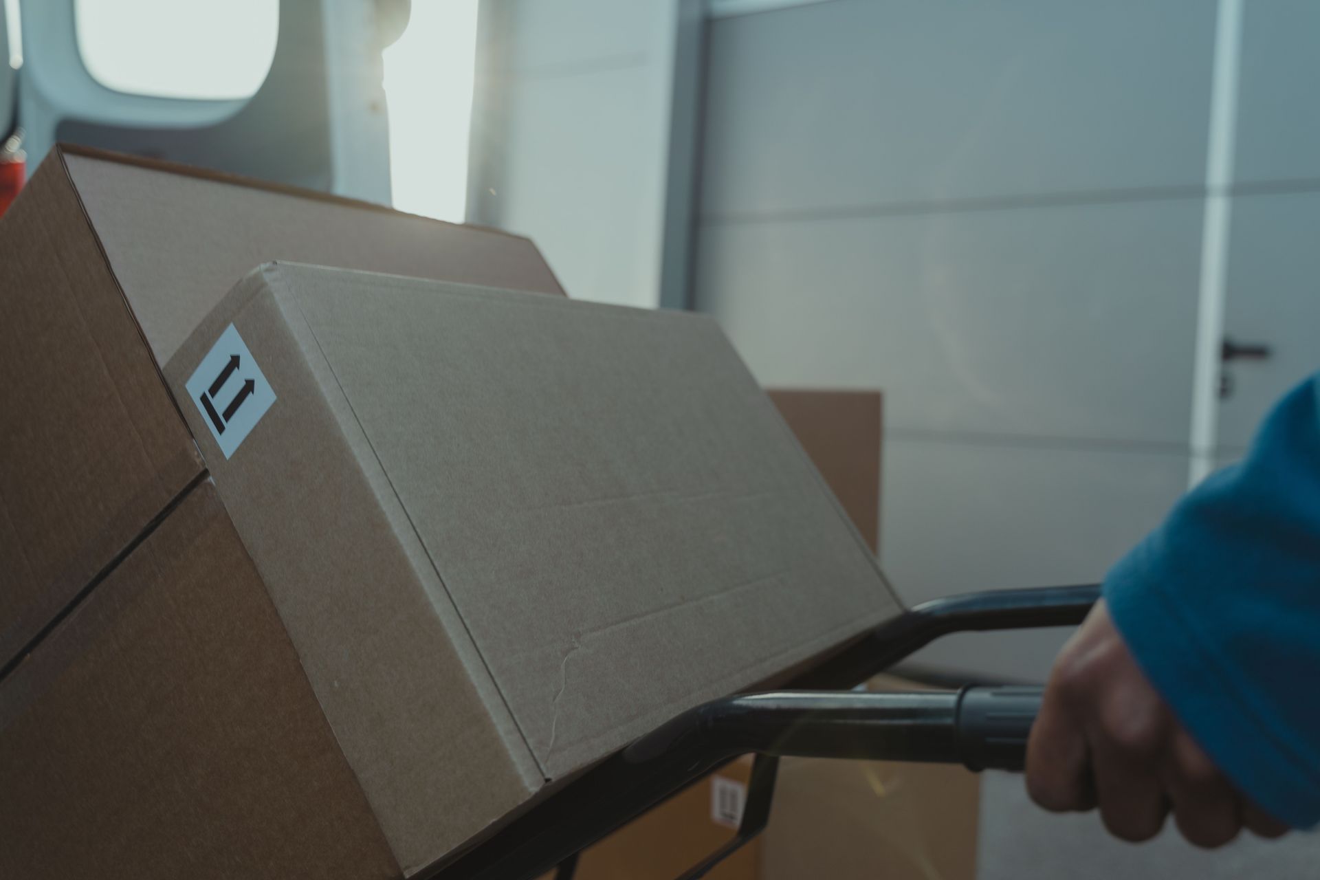 A cardboard box on a trolley inside a delivery van, showcasing logistics and shipment.